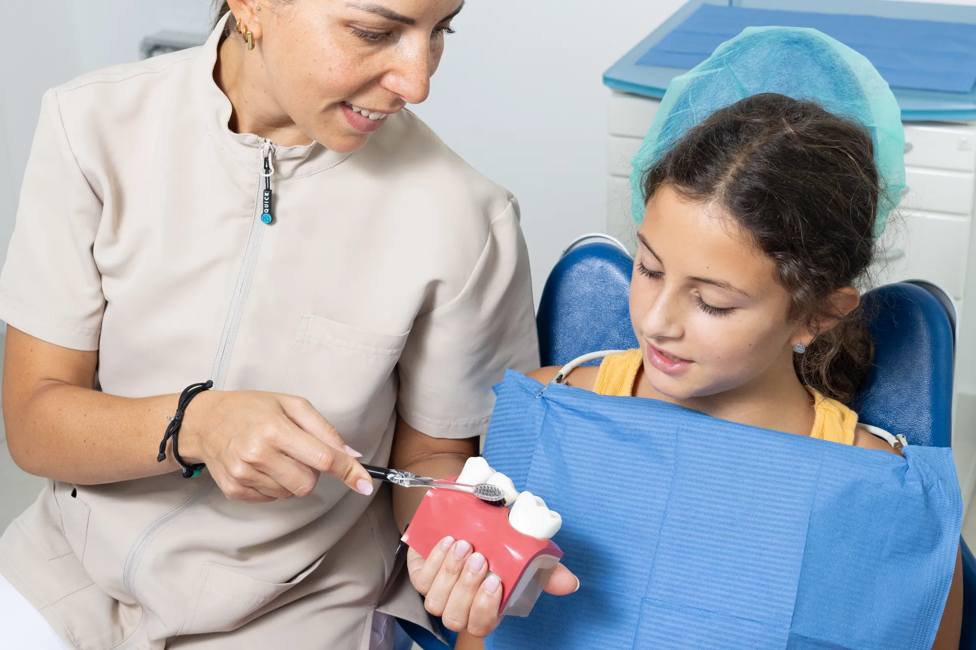 Una dottoressa mostra a una bambina come lavarsi i denti su un modello